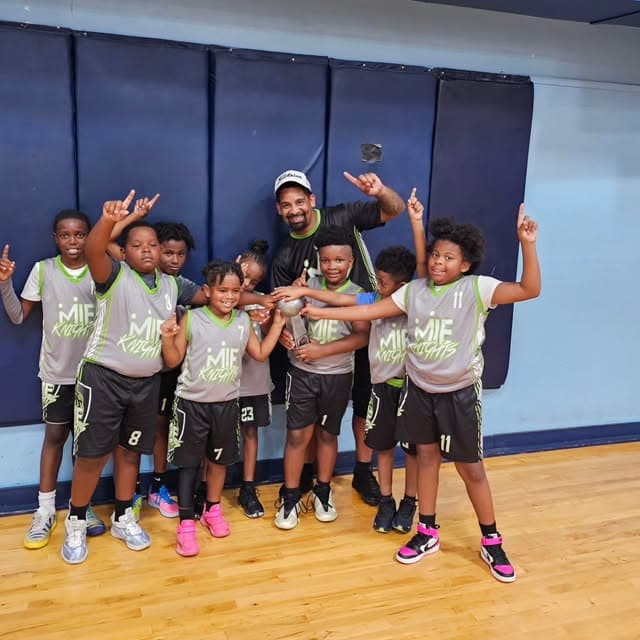 MIE Knights basketball players and a coach gathering together in an indoor gym