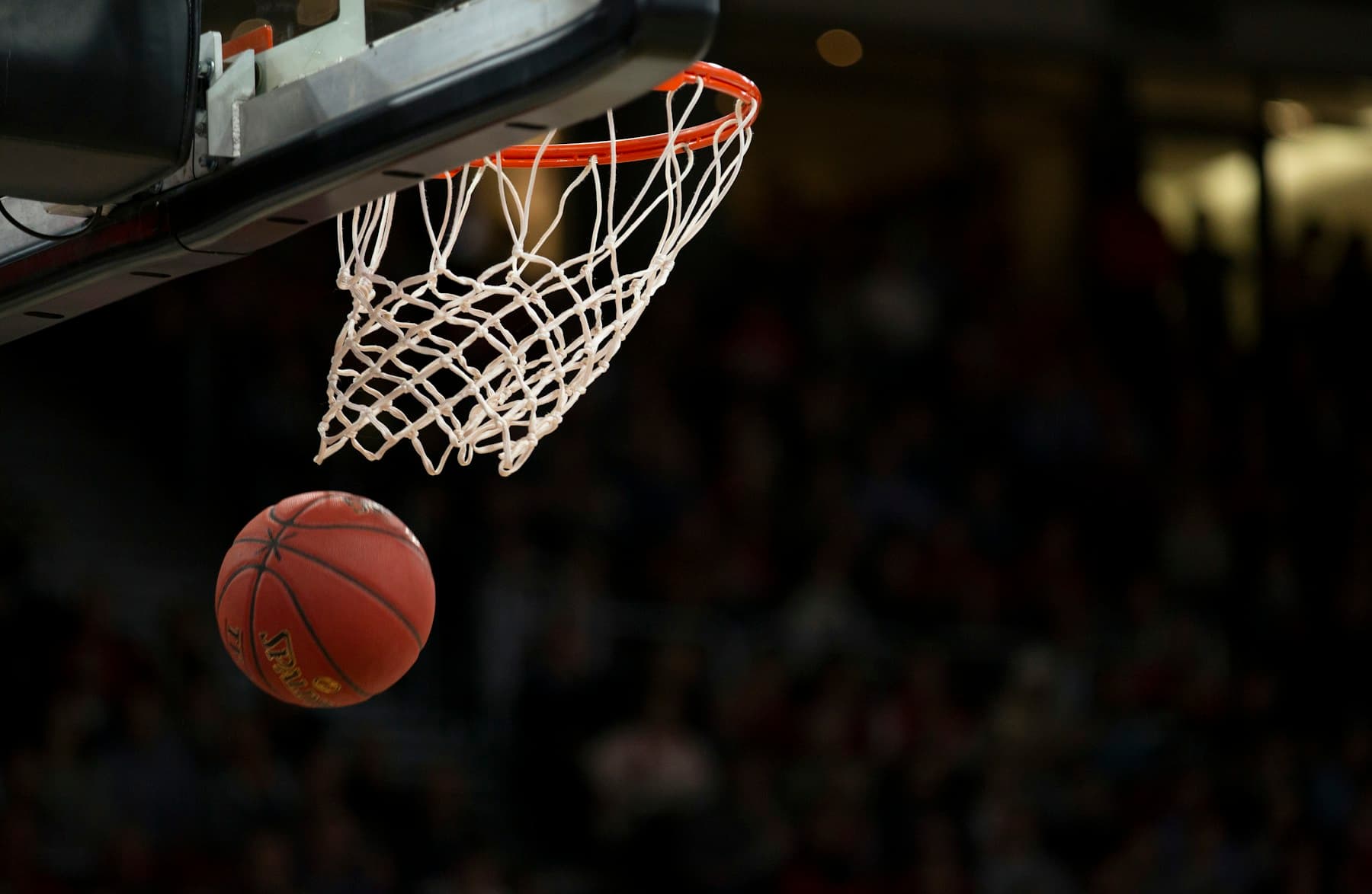 Stock basketball photograph of a ball beneath an indoor hoop